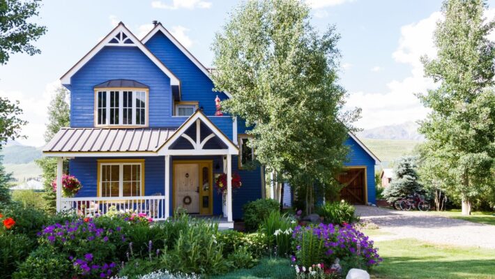 two storey home with blue siding and a garden in bloom